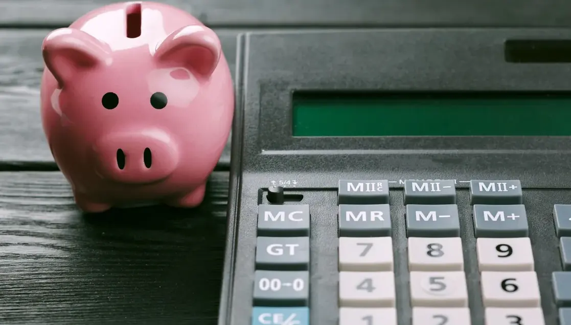 Cofre em formato de porquinho ao lado de calculadora
